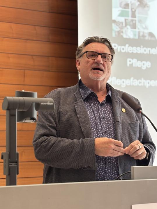 Franz Wagner hat auf dem Pflegetag Niedersachsen 2025 über die neuen ICN-Definitionen von "Nursing" und "a Nurse" und ihre offiziellen deutschen Übersetzungen gesprochen.